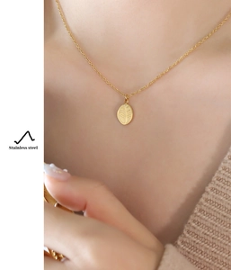 Macro view of gold stainless steel necklace pendant with detailed leaf pattern engraving