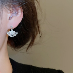 Close-up of fan-shaped silver drop earrings with zircon crystals worn by a model