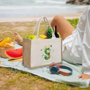 Detail of canvas tote bag with floral S print and rope handles on a sunny beach setting