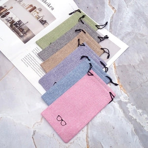 Linen drawstring sunglasses pouches in six colors on marble surface with magazine