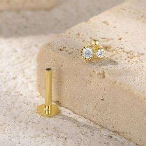 Detail of gold S925 silver earring with triple stone cluster on natural stone