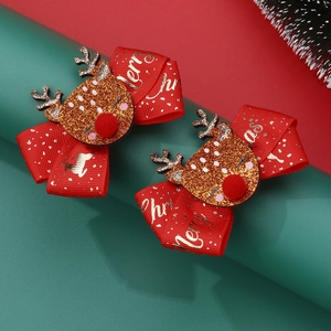 Close-up of red ribbon bow hair clips with glittery golden reindeer for Christmas