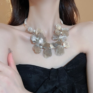 Detail view of woven metal mesh flower petals with pearl accents on a statement necklace