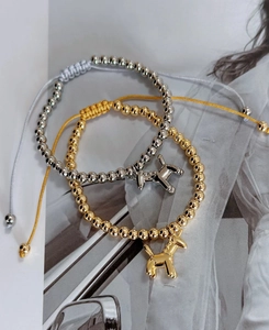 Detail of adjustable braided bracelets with polished gold and silver balloon dog charms