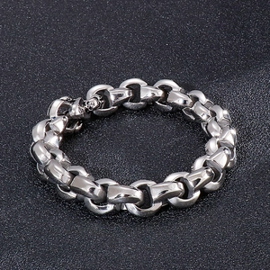 Close-up of silver D-link chain bracelet with a skull charm on black textured background