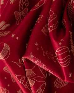 Detailed macro view of red festive fabric with golden Christmas patterns and lace edge