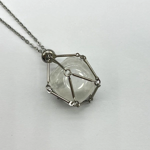 Macro detail of clear faceted gemstone inside a silver stainless steel mesh pendant necklace