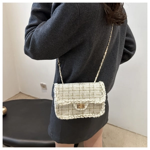 Detail of tweed chain strap and woven fabric texture on a cream-white crossbody bag