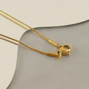 Close-up of gold snake bone chain necklace showing lobster clasp and link details