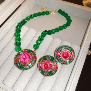 Detail of vintage necklace set with green beads and pink gemstone in velvet box