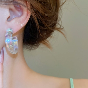 Close-up of iridescent acrylic C-shaped hoop earring on model with rainbow finish