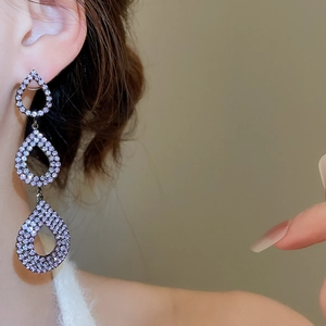 Detailed view of layered purple crystal water-drop earrings on female model