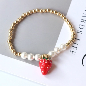 Gold-plated strawberry pendant pearl bead bracelet for women on minimalist background