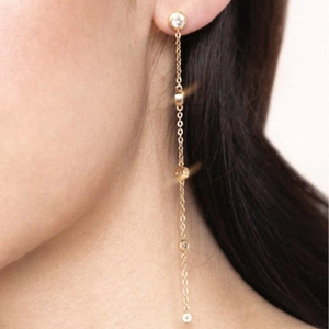 Macro detail of long gold tassel drop earrings with sparkling cubic zirconia on a model