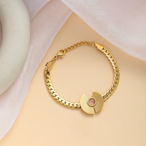 Detail of gold bracelet with pink gemstone center on elegant silk fabric background