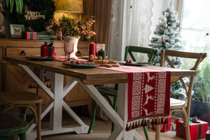 Close-up of red Christmas table runner featuring white reindeer motifs and colorful tassels