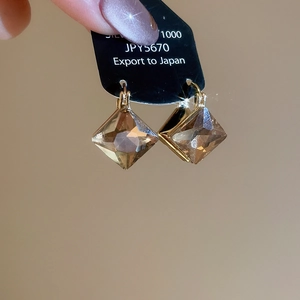 Detail view of champagne square-cut crystal earrings with gold geometric setting