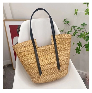 Vue détaillée du tressage en paille naturelle et des anses en cuir noir d'un sac cabas