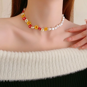 Detail of beaded flower and irregular pearl necklace on model neck and collarbone