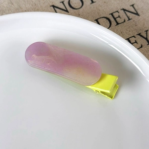 Close-up of purple and yellow gradient hair clip with golden glitter and metal clip