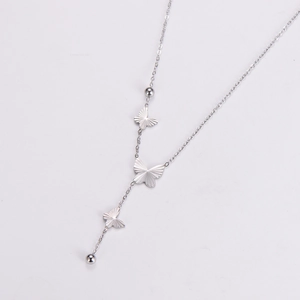 Macro detail of silver butterfly pendant bracelet with delicate chain and bead accents
