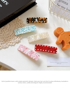 Detailed macro view of 5-piece acetate hair clips with inlaid white pearls and floral patterns