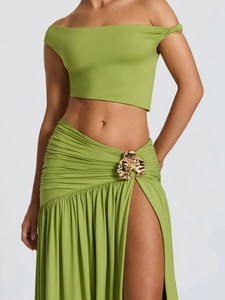 Detail of green two-piece set featuring gold flower buckle and pleated skirt waist
