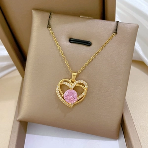 Vue macro du collier double cœur doré avec pierre rose centrale et cristaux brillants
