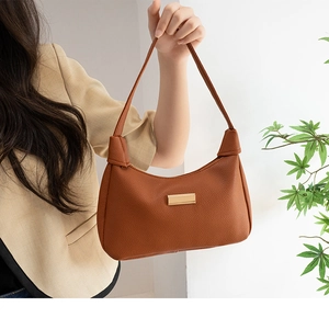 Close-up of brown hobo bag featuring litchi grain texture and a gold metal logo plate