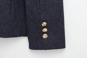 Close-up of denim blazer cuffs with three golden textured buttons on dark blue fabric