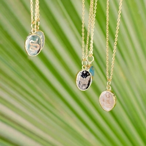 Vintage stainless steel necklace with butterfly and snake pendants on palm leaf background