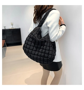 Detail of a black quilted cloud bag shown on a model to demonstrate size and style