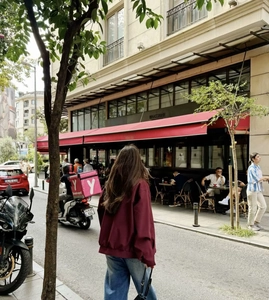 Street style view of a burgundy bomber jacket paired with casual denim jeans on city sidewalk