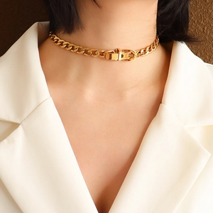 Golden chunky NK chain choker with buckle detail on a model in a white blazer