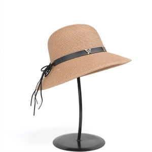 Close-up of straw sun hat featuring a black leather band and golden metal butterflies