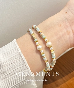 Detail of layered bracelet featuring natural pearls, blue stones, and golden beads