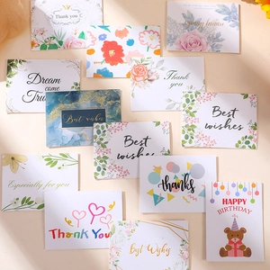 Close-up of assorted paper gift cards with floral and cartoon bear designs and best wishes
