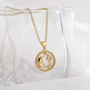 Detail shot of a gold necklace featuring a celestial pendant with moon and star zircon accents
