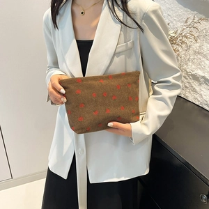 Brown corduroy strawberry pattern tote bag held by model in professional white blazer