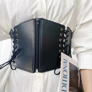 Detail of wide black elastic waist belt featuring silver zipper and lace-up metal eyelets