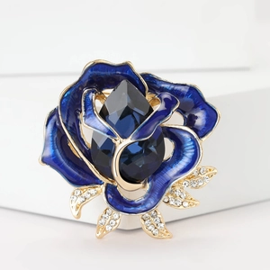 Detailed close-up of blue enamel rose brooch with gold leaves and crystal droplet