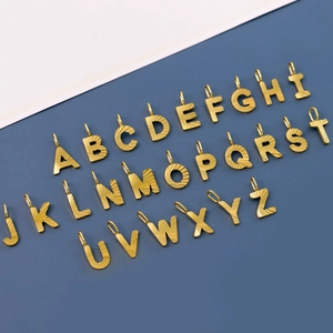 Macro detail of 26 golden stainless steel letter pendants A-Z with textured finish