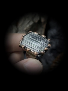 Macro detail of natural green tourmaline raw stone with bronze textured ring setting