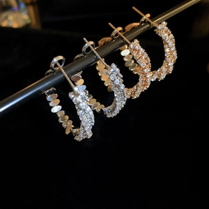 Macro detail of silver and gold hoop earrings with sparkling paved cubic zirconia stones