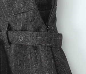 Detail of dark gray striped skirt pants showing zipper closure and waistband loops
