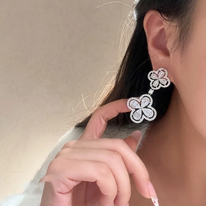Elegant silver clover drop earrings with micro-p鑲zirconia on a female model