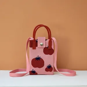 Detail of pink knitted mobile phone bag with red tomato patterns and round handle