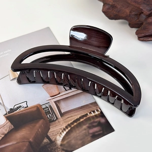 Detail of a large tortoise shell hair claw clip on an open book with minimalist aesthetic