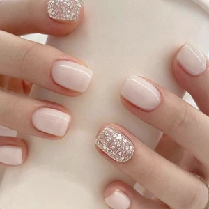 Close-up of milky white and silver glitter press-on nails on a hand holding a prop
