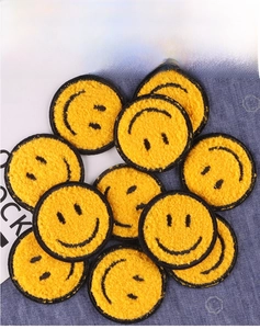 Close-up of yellow chenille smiley face patches on blue denim fabric for DIY clothing